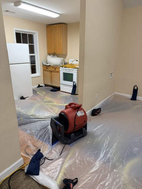 Active kitchen water damage drying with air mover and plastic floor protection in a Texas home